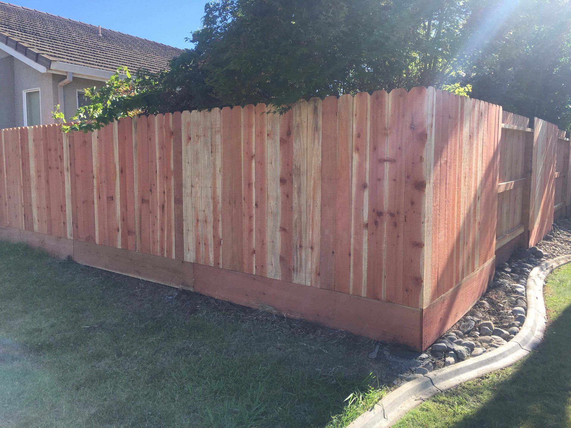 A wooden fence is in the backyard of a house.