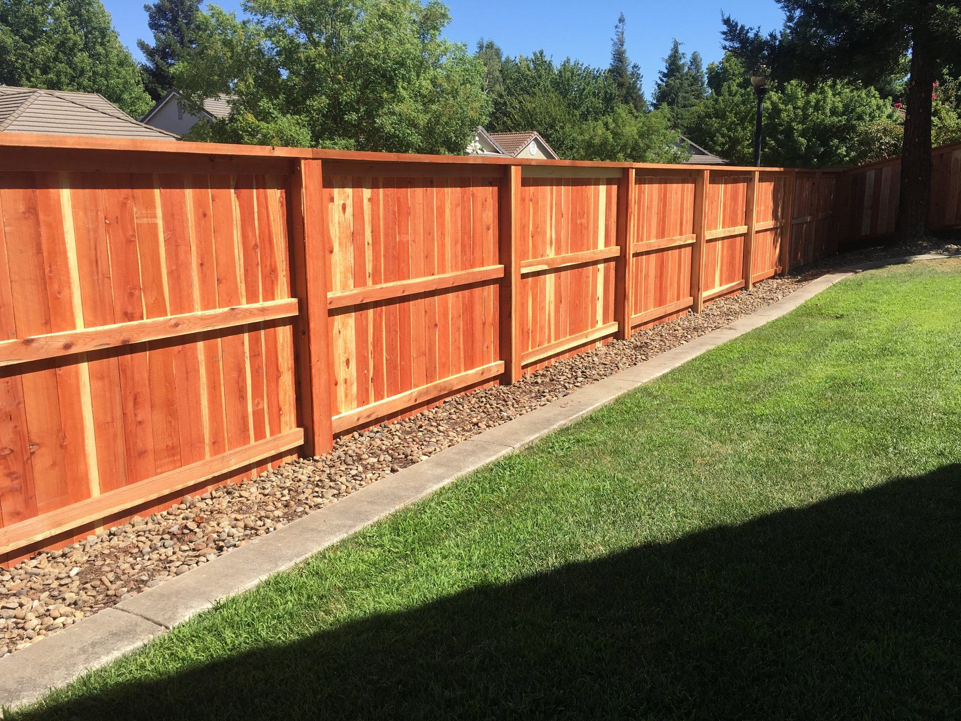 A wooden fence surrounds a lush green yard.