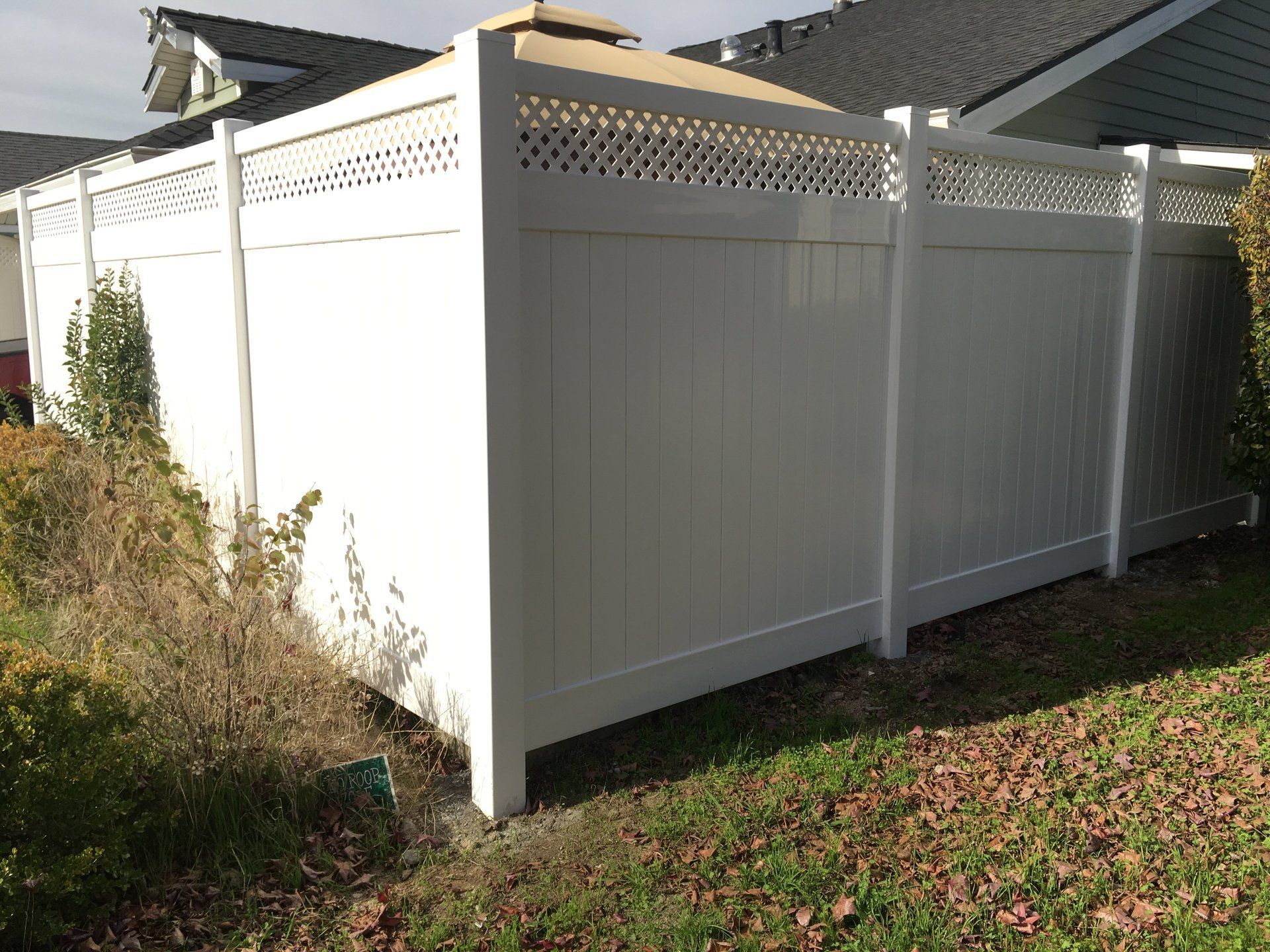 A white fence is sitting in the grass in front of a house.