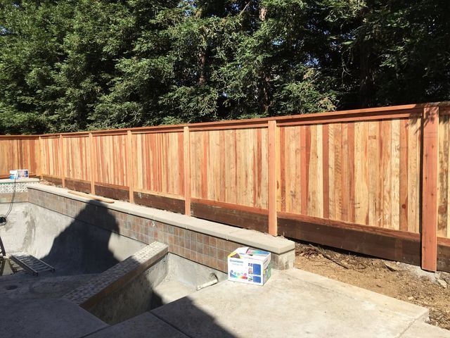 A wooden fence is surrounding a swimming pool.