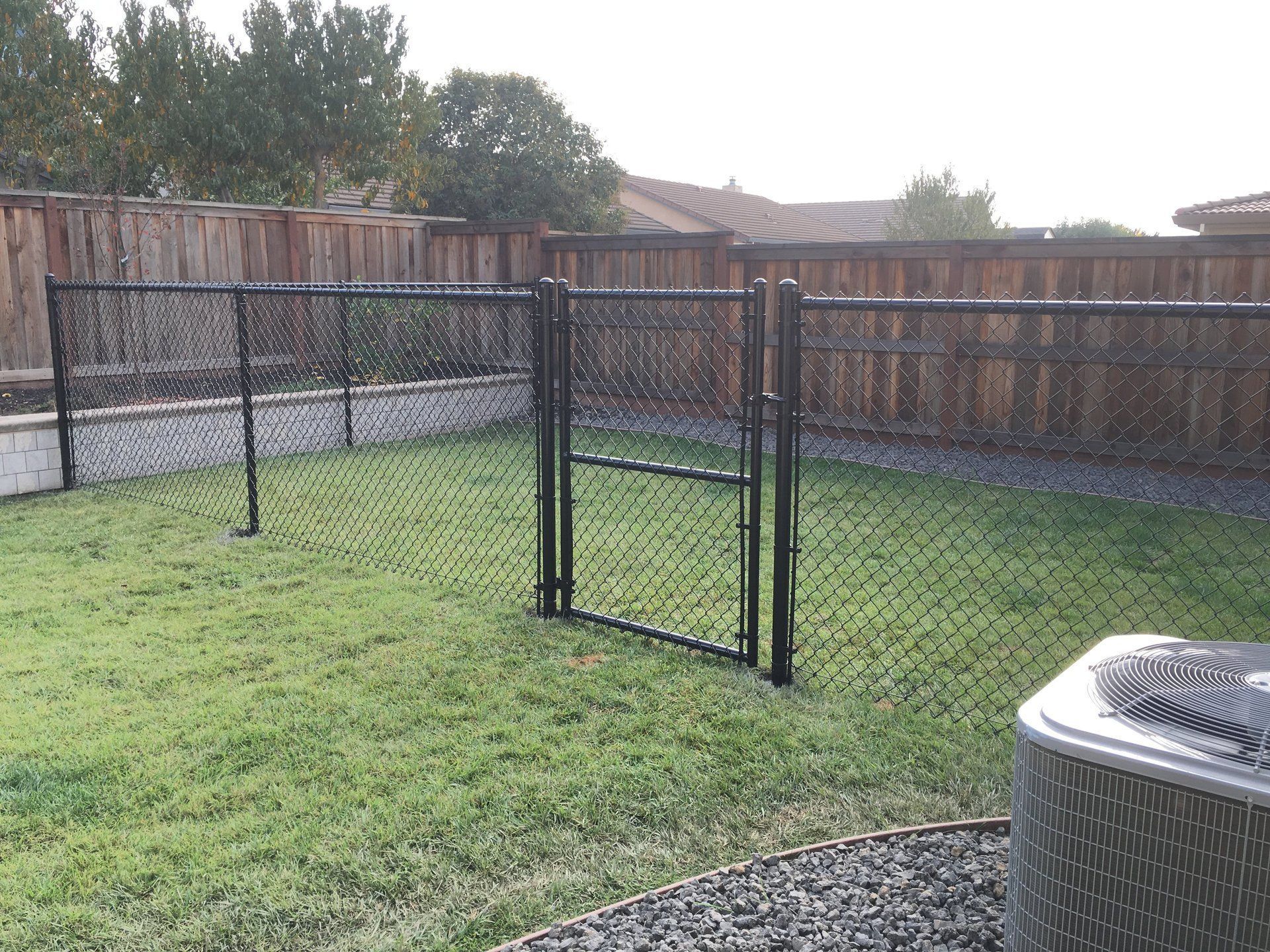 A backyard with a chain link fence and a gate.
