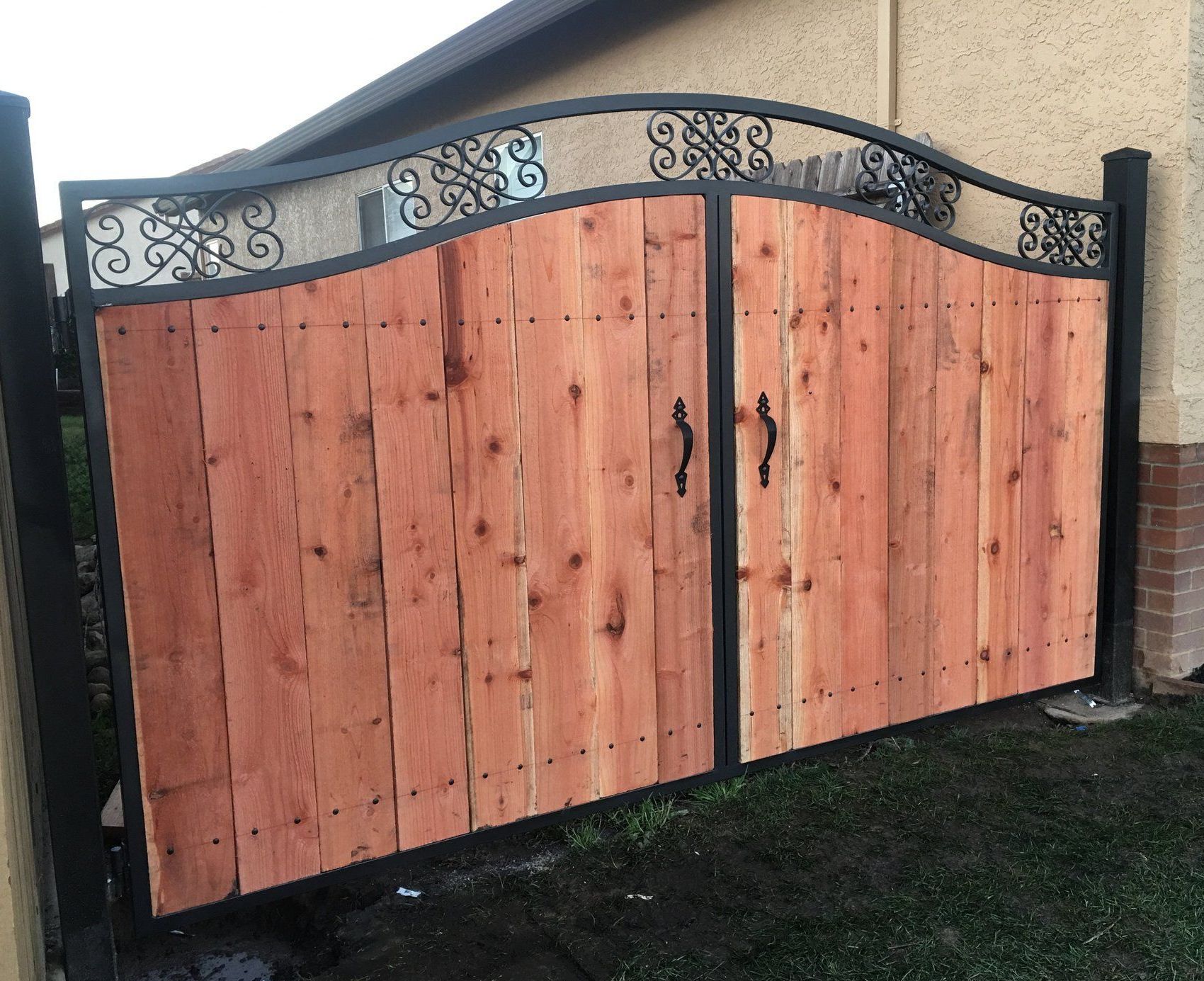 A wooden gate with a metal frame is in front of a house.