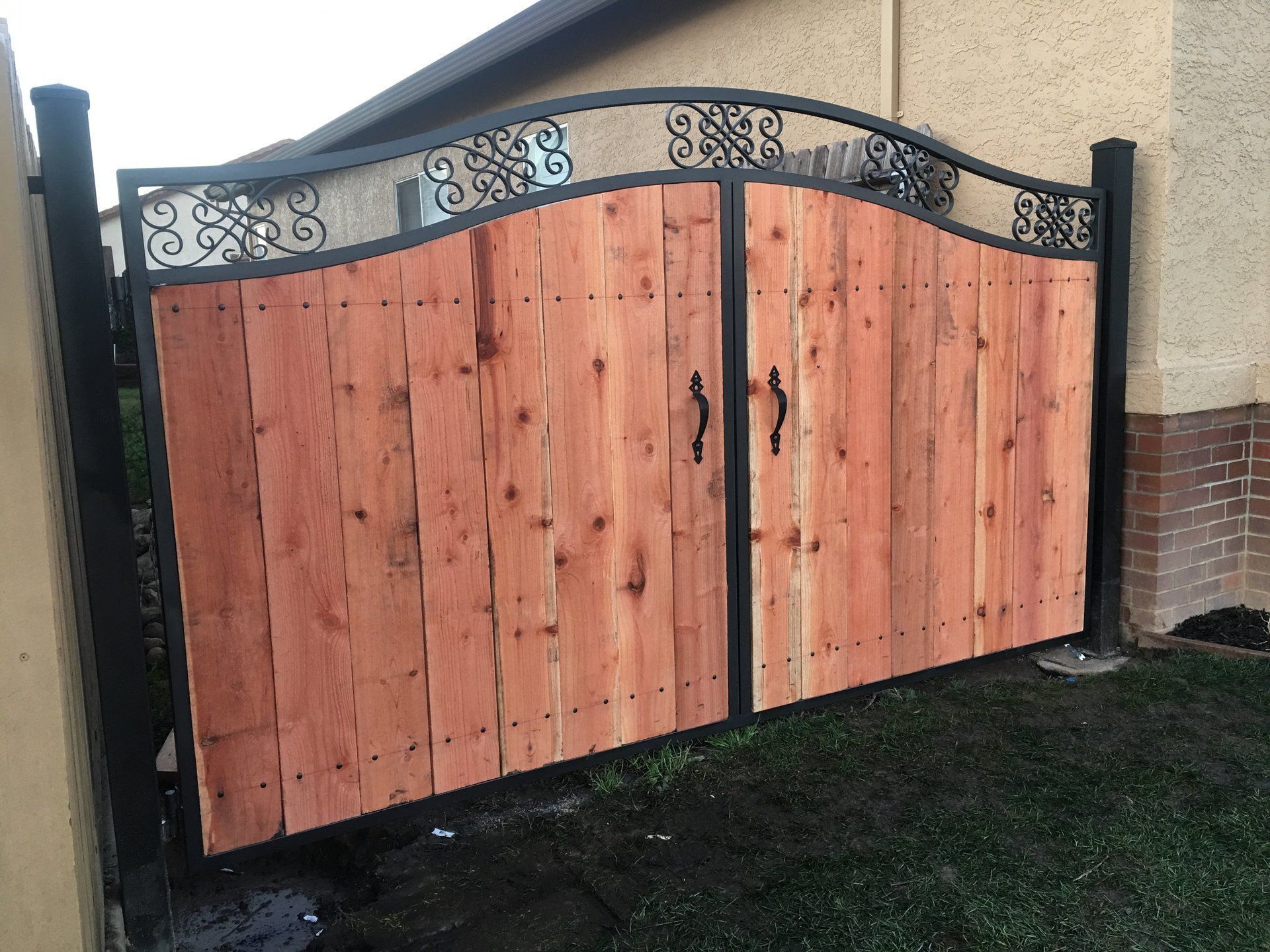 A wooden gate is sitting in front of a brick building.