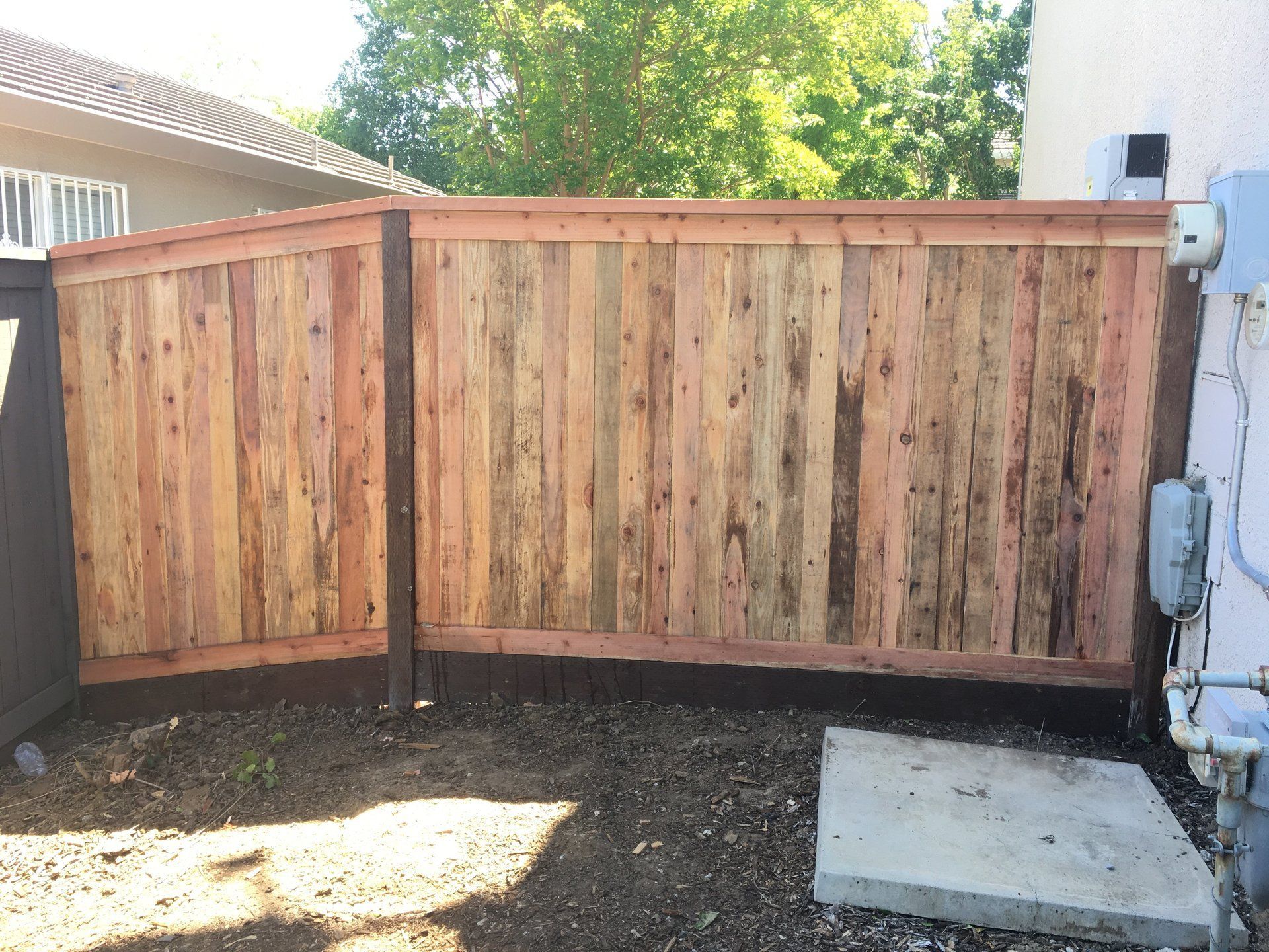 A wooden fence is in the backyard of a house.