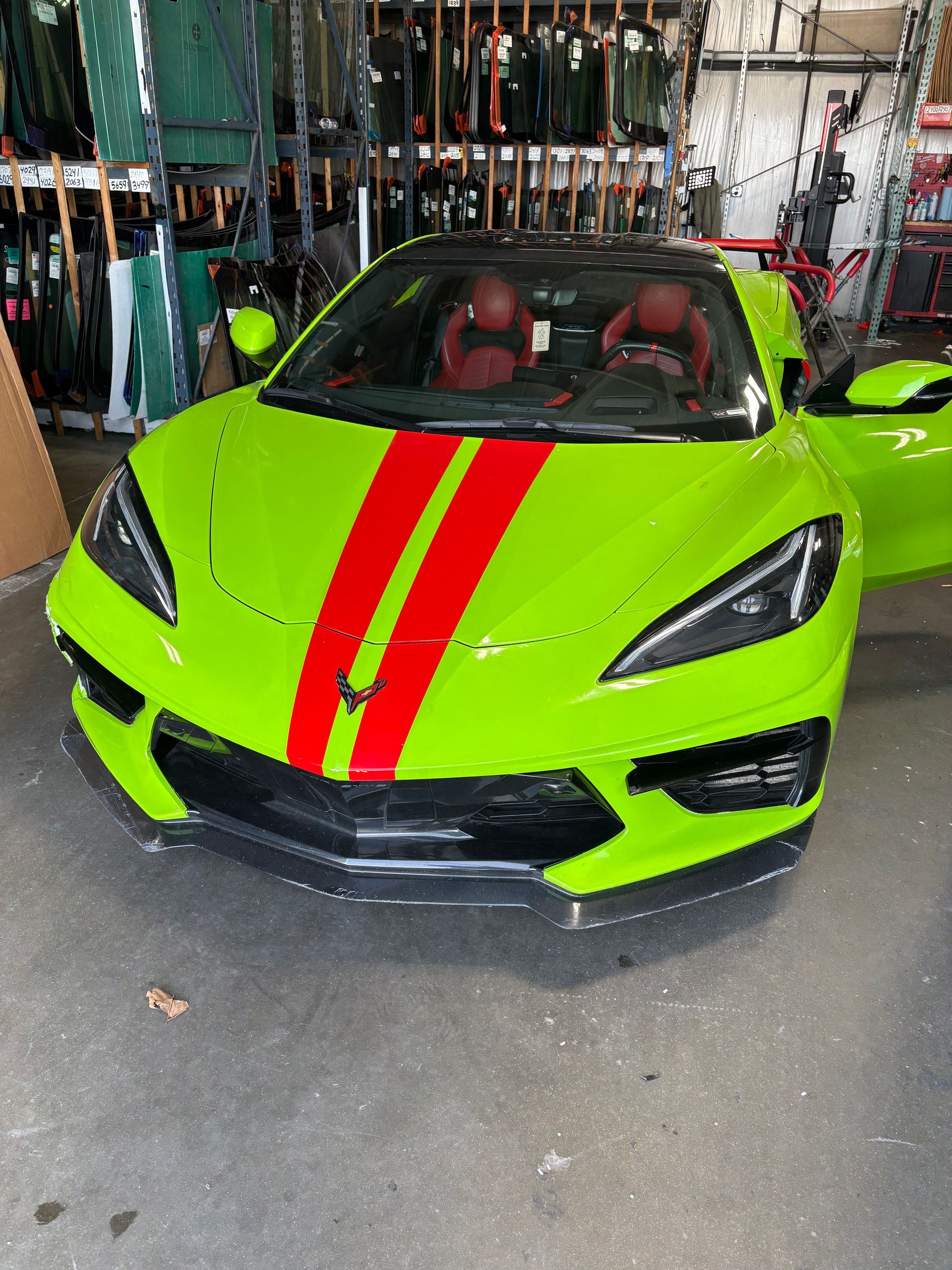 Bright green sports car with red racing stripes, parked indoors.