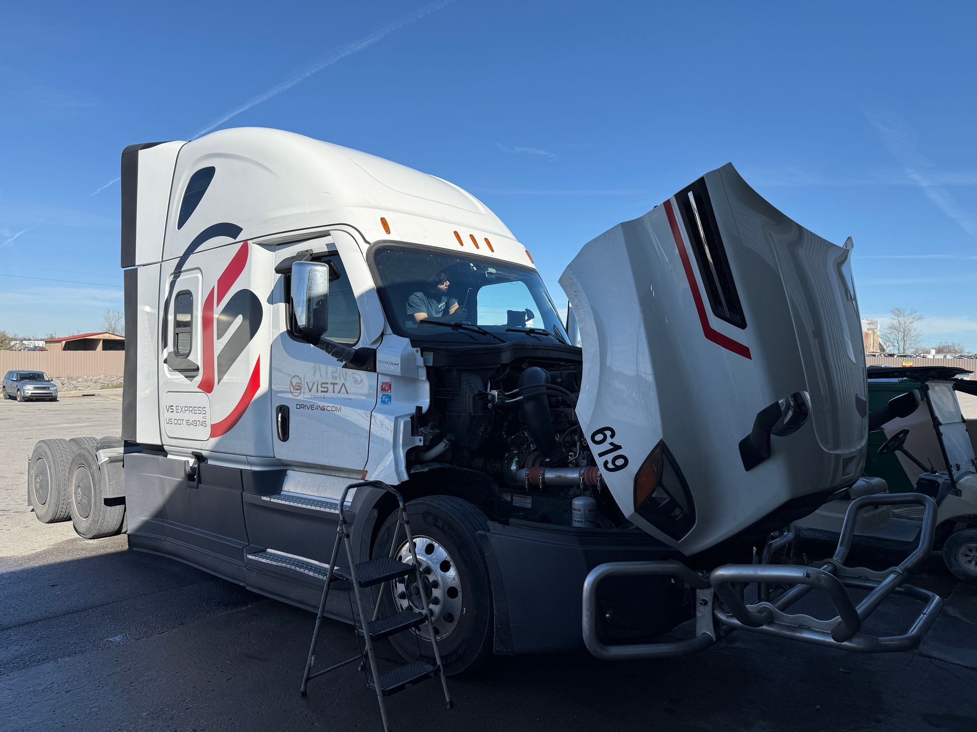 Person installing a windshield on a silver Lexus sedan.