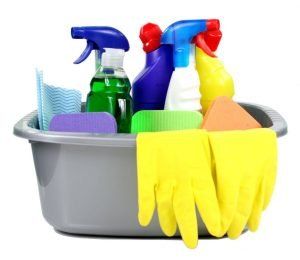 Cleaning supplies in a gray basin: spray bottles, sponges, gloves.