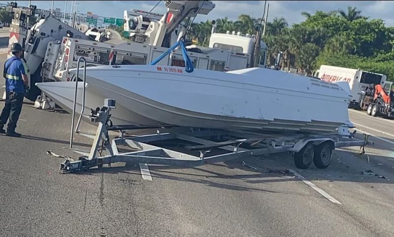 A boat is on a trailer on the side of the road