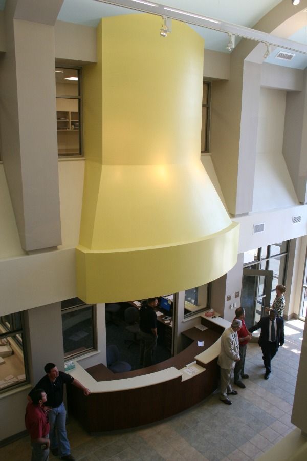 Interior view of building with a yellow structure overhead and people at a reception desk.