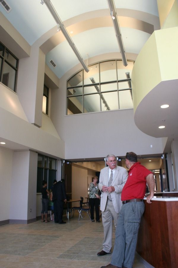 Two men talking inside a modern building with high ceilings, other people in the background.