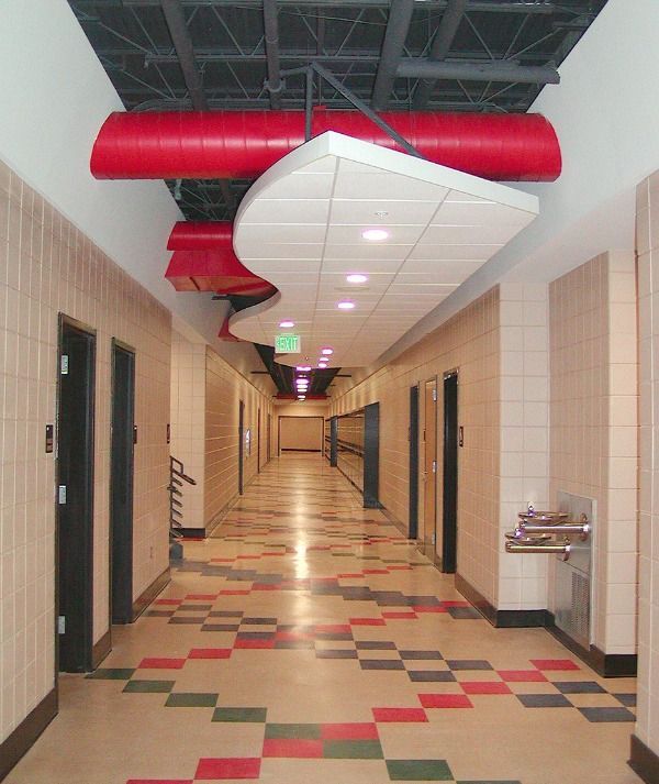 Hallway with checkered floor, red ductwork, cream-colored walls, and doors; a water fountain on the right.