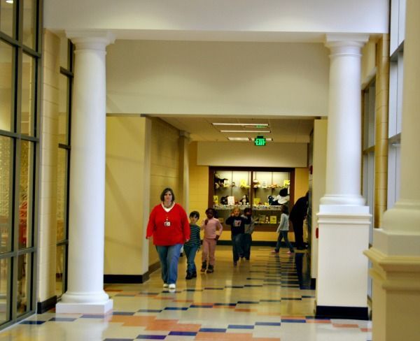 Hallway with columns; woman and children walking.