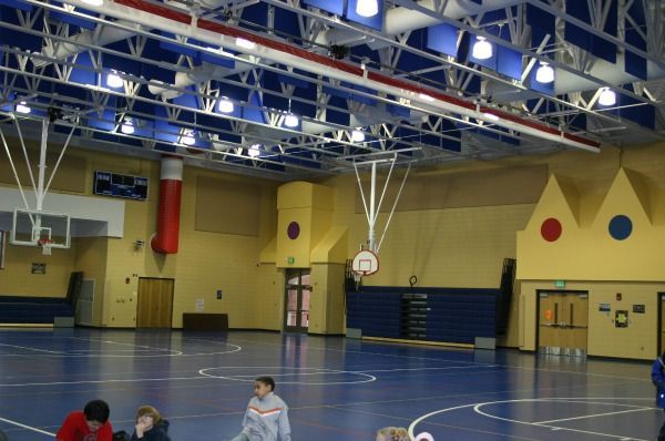Gym interior with basketball court, high ceiling, and people.