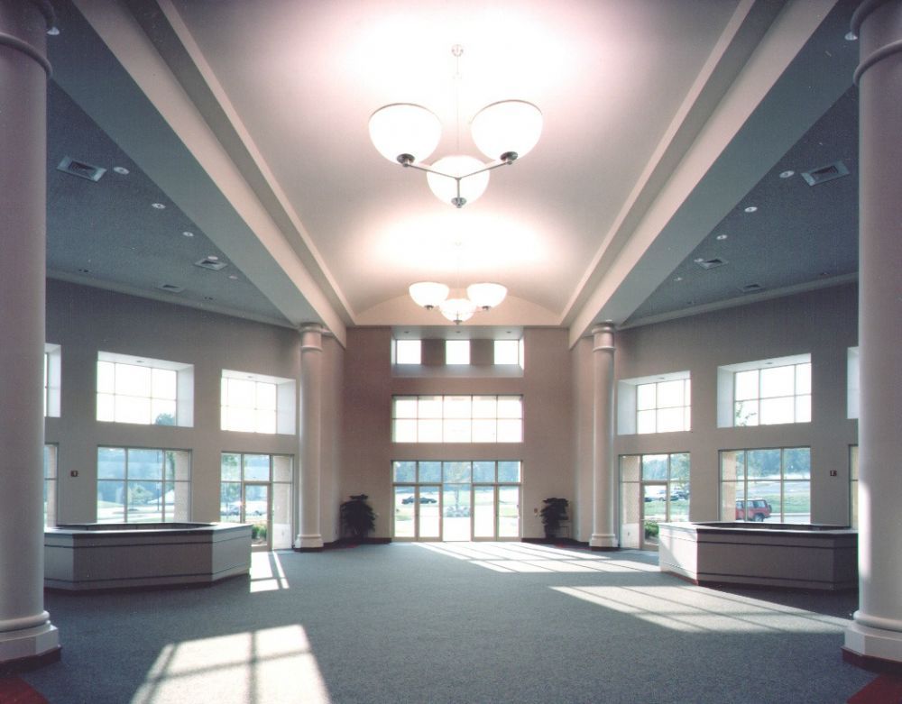 Spacious, bright foyer with white pillars, windows, and chandeliers. Entrance doors in the center.