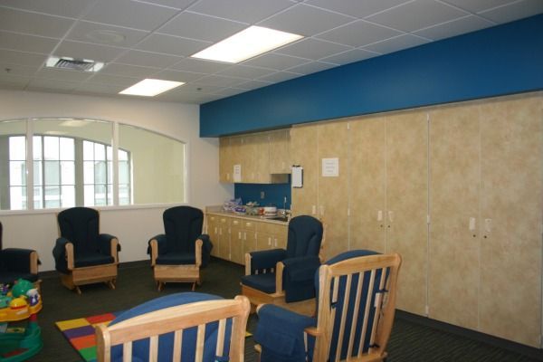 Waiting room with blue armchairs, pale walls, and a blue stripe; a window is visible.