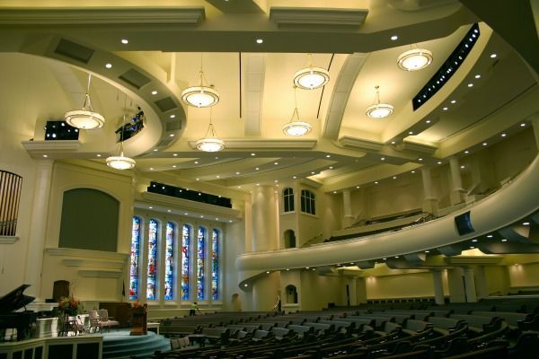 Interior of a large sanctuary with curved walls, stained glass windows, and rows of seating.