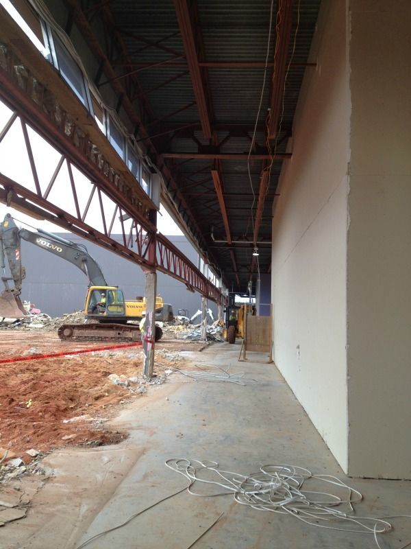 Construction site with heavy machinery and exposed building structure next to a smooth white wall.