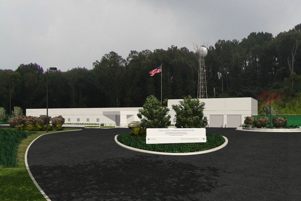 White building with US flag, water tower, and sign on black asphalt road.