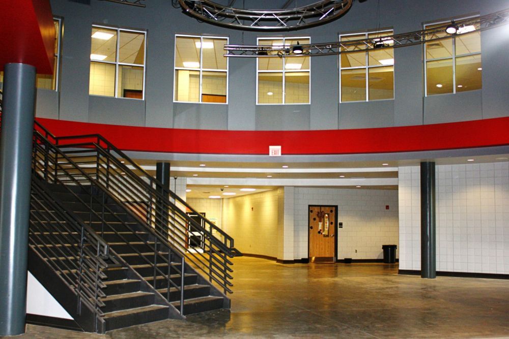Indoor view: gray and red walls, staircase, windows, lights, and a door.