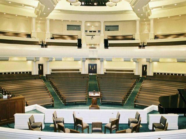Inside a church auditorium with rows of seating, stage, and pulpit.