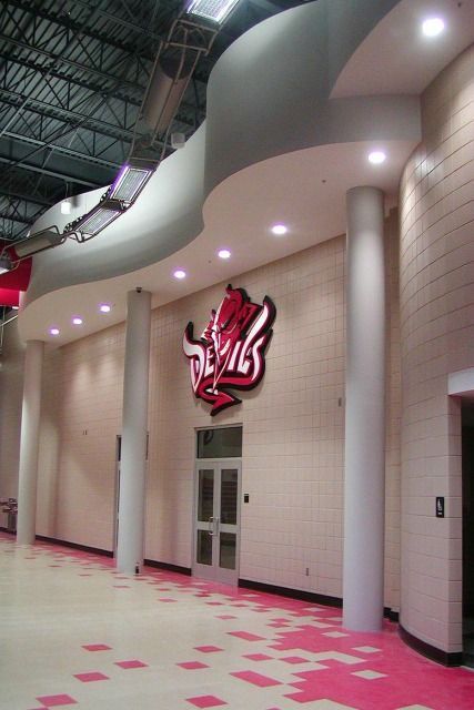 School hallway with a Devils logo on the wall. Red, white, and pink color scheme.