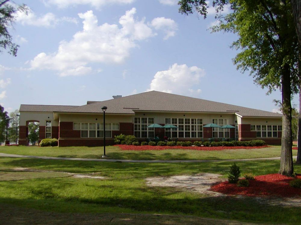 Building with red brick and beige siding, grassy lawn, sunny day.