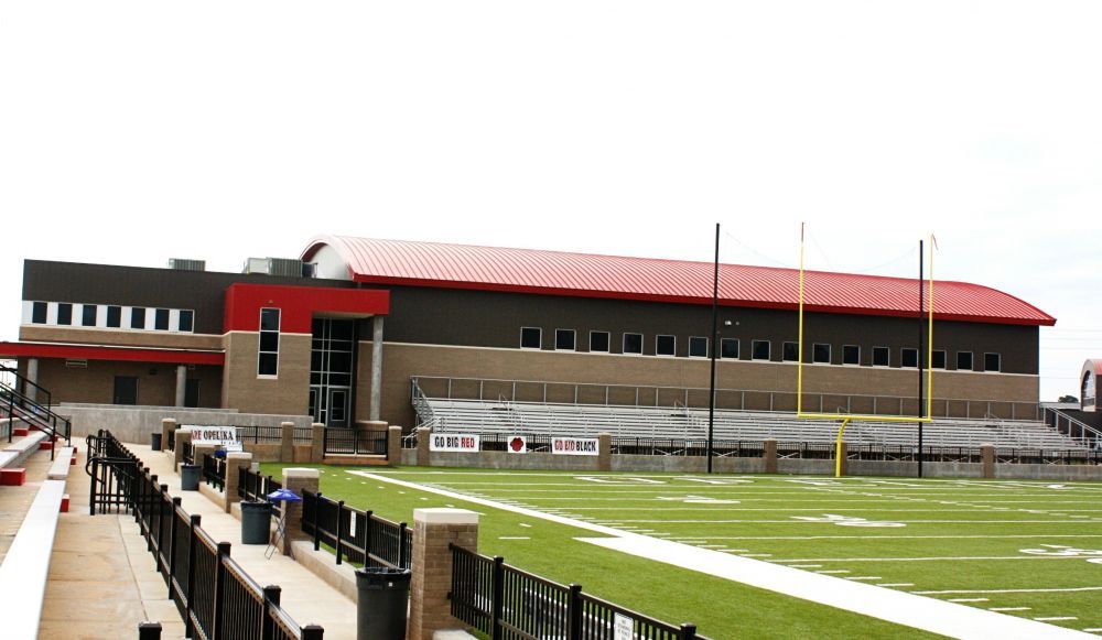 Football stadium with a building, red roof, and green field.