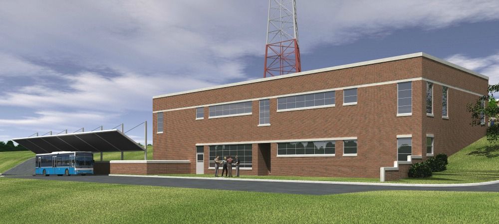 A brick building with a bus shelter and radio tower on a green hill.