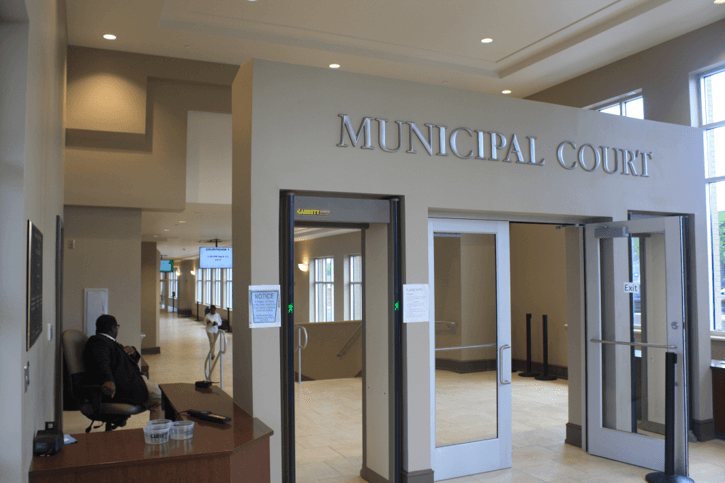 Interior of a municipal court building with signage, security, and doorway entry.