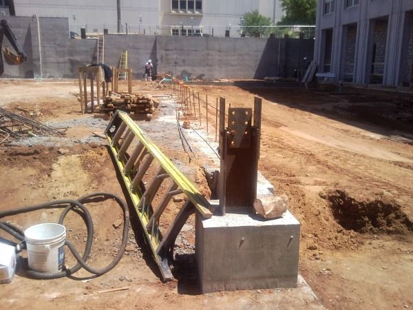 Construction site with a ladder, metal beams, and concrete foundation.