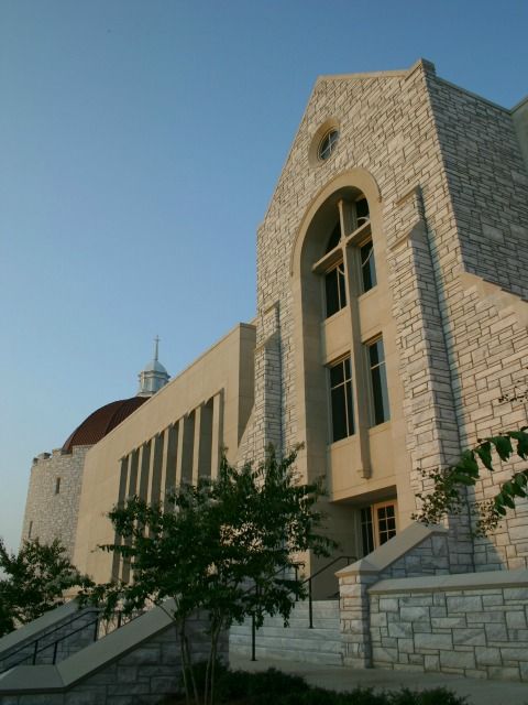 Stone church building with a cross, under a blue sky.