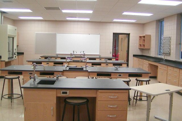 Empty science lab with lab tables, stools, and a whiteboard.
