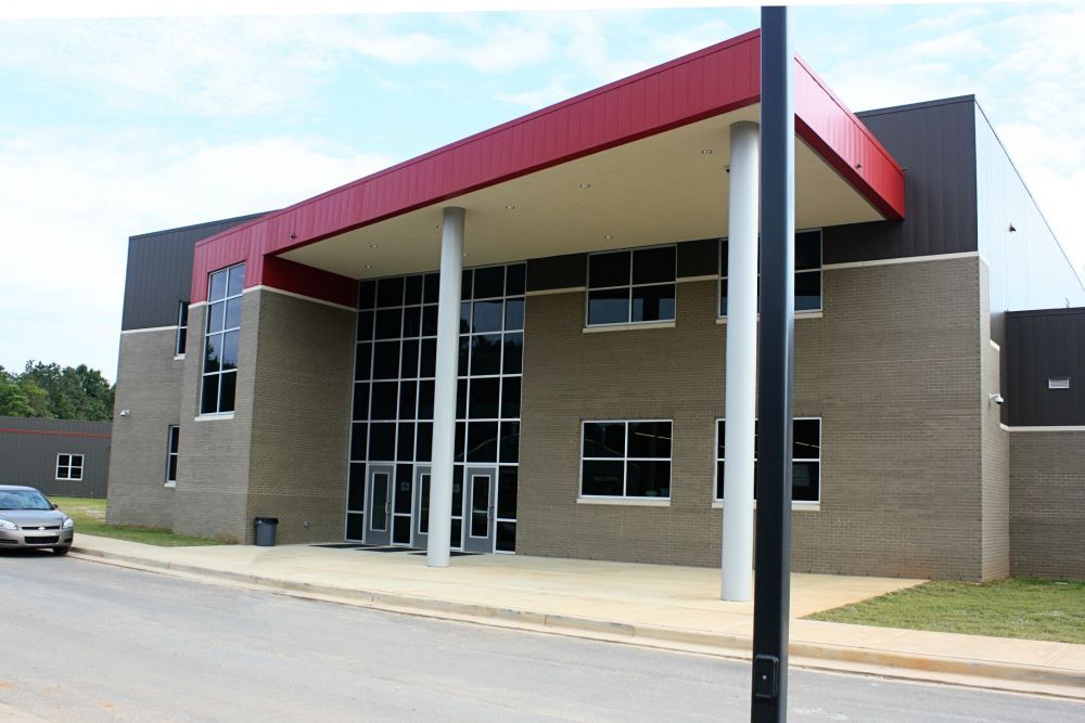 School building with red overhang, glass entrance, and brick facade.