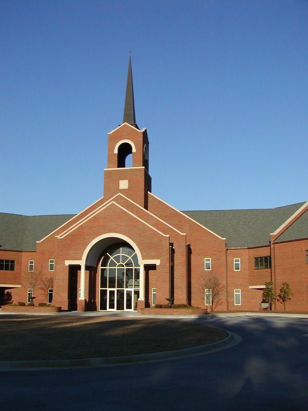 Brick church building with a steeple, arched entrance, and clear blue sky.