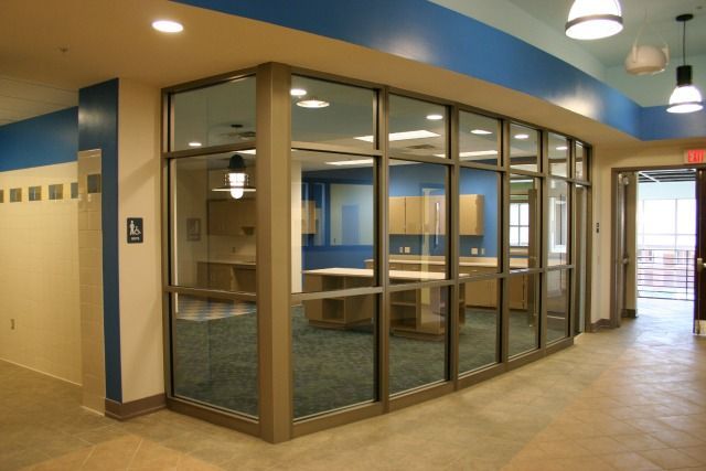 Glass-walled office space inside a hallway with blue and beige walls, and open doorway.