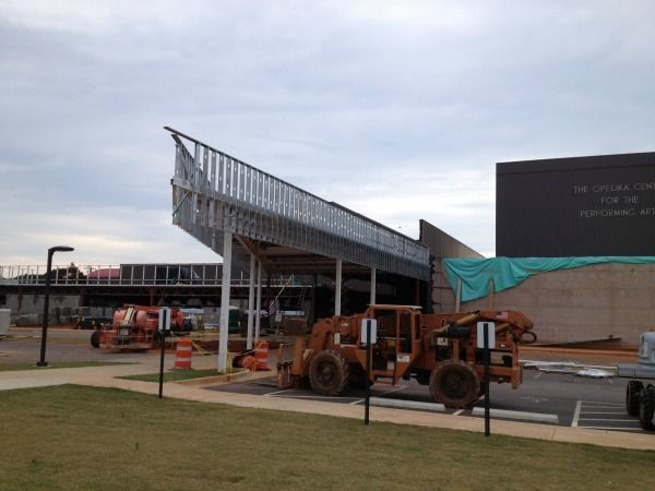 Construction site with metal framework and heavy machinery under a cloudy sky.
