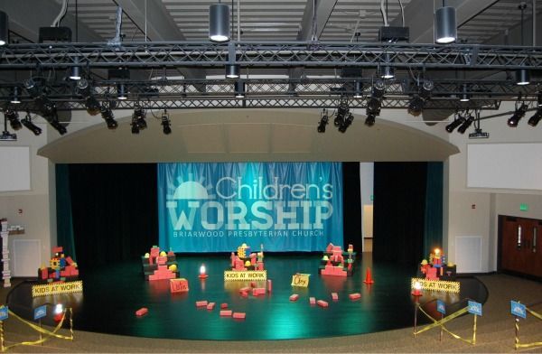 Children's worship stage: teal backdrop, blocks, stage lights, and construction cone.