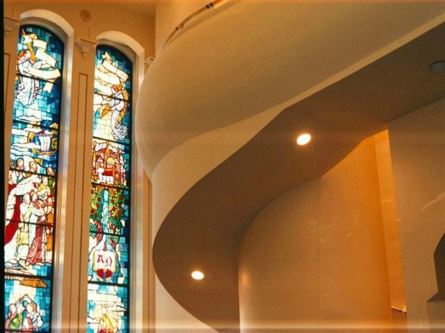 Stained glass windows next to a curved, cream-colored wall with two recessed lights.