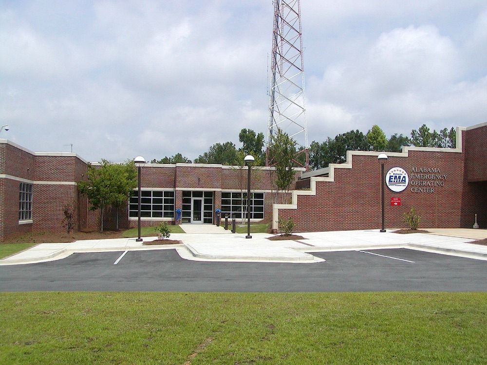 Brick building with a radio tower, a sign, and a parking lot.