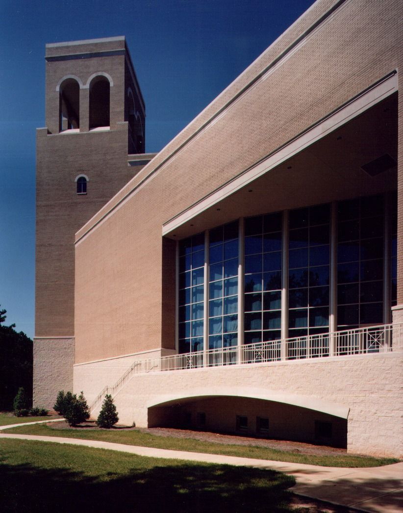 Brick building with a tall tower and arched windows, set against a blue sky.
