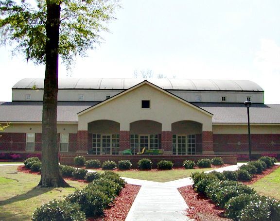 Building with arched entryways, a brick facade, and a dark roof, with a path leading to the entrance.