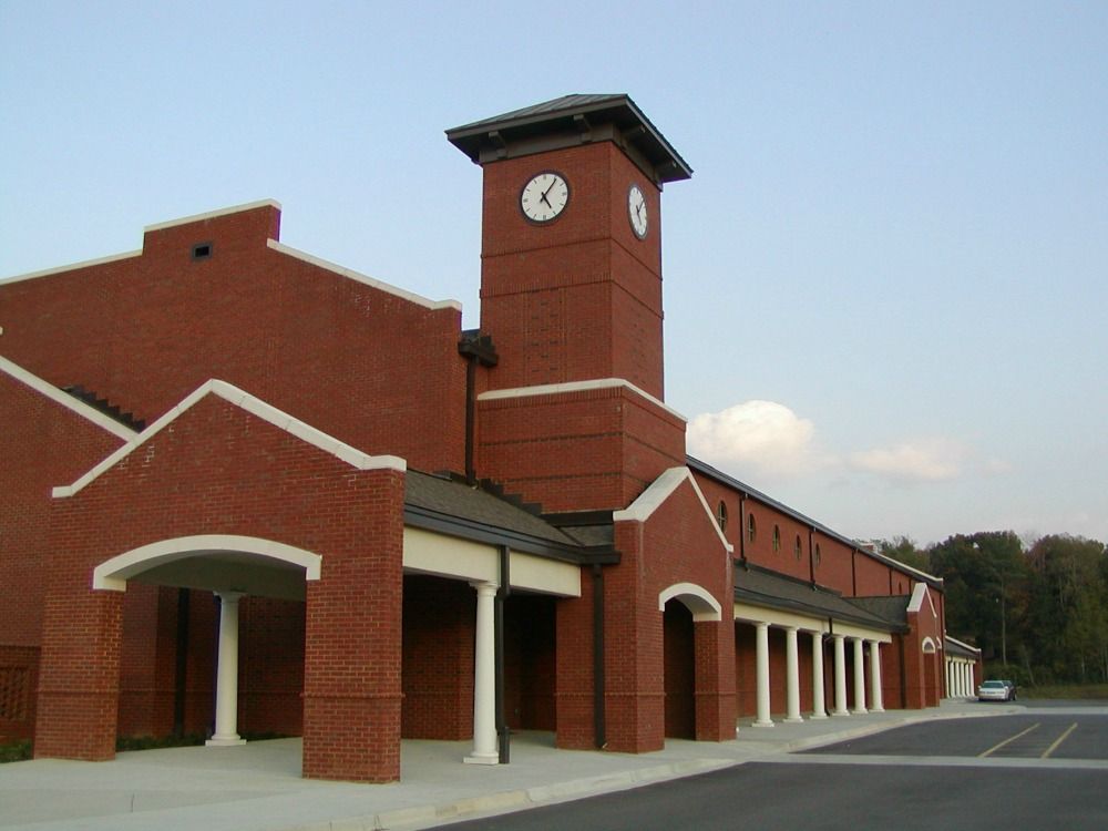 Red brick building with clock tower and white columns under a blue sky.