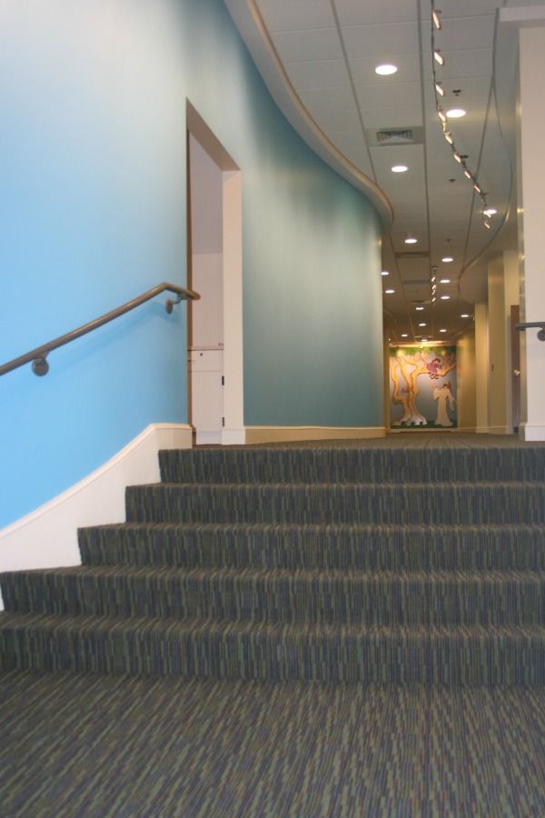 Staircase with blue wall and handrail leads to a hallway.