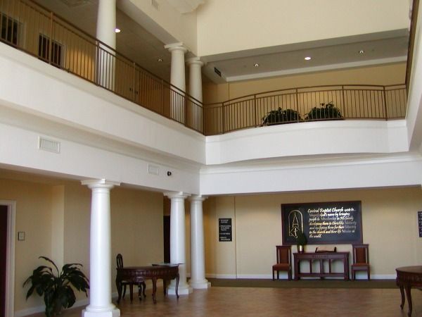 Interior of a building with white columns, balconies, and a wall display.