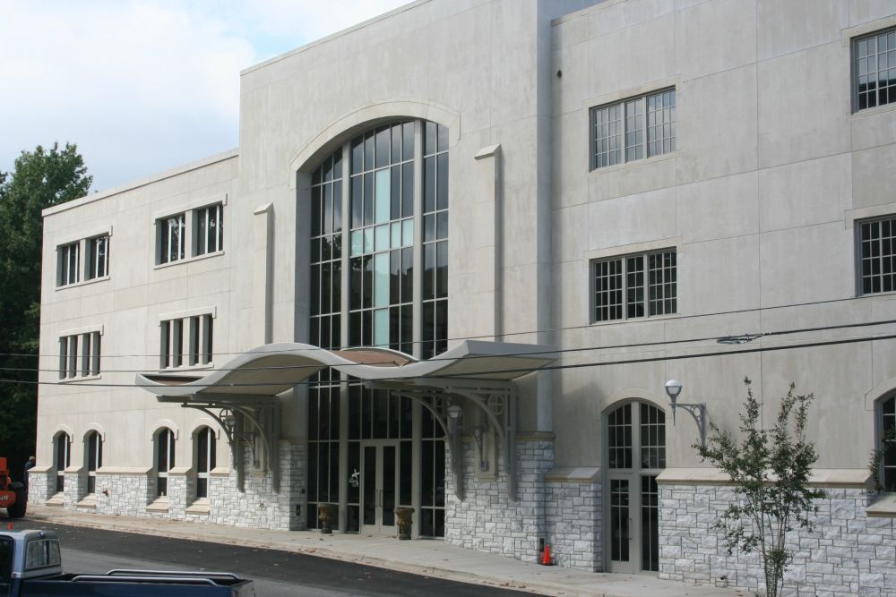 White building with large arched window over entrance and awning; windows on upper levels.