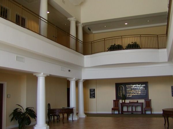 Spacious, multi-level interior with white pillars, balconies, and a seating area, neutral colors.