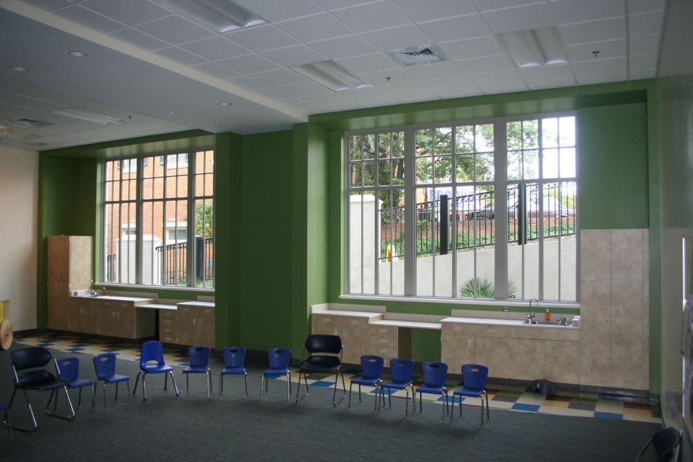 Room with green walls, large windows, blue chairs arranged in a circle, and built-in storage.