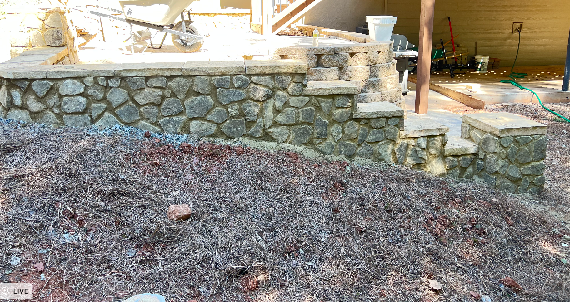 Work in progress by RC Landscapes featuring stone wall construction and pine straw mulching.