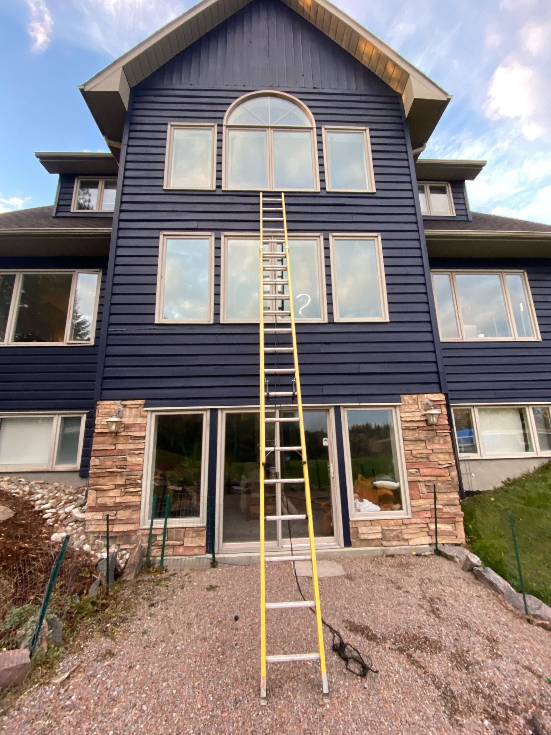 A large blue house with a yellow ladder in front of it