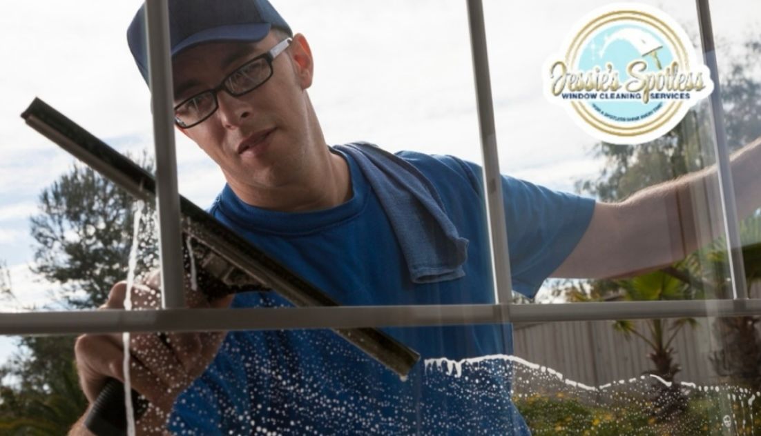 A man is cleaning a window with a squeegee.